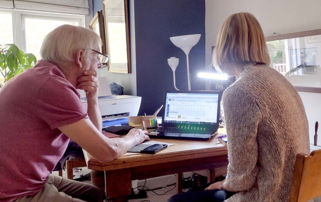 Two people looking at a laptop as part of the Tech Angels project. 