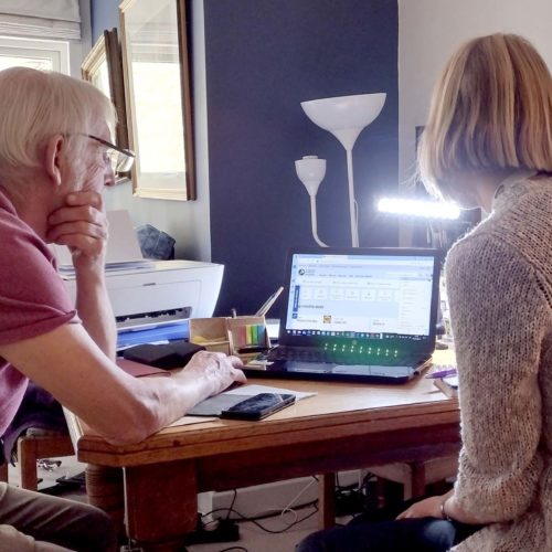 Two people looking at a laptop as part of the Tech to Community project