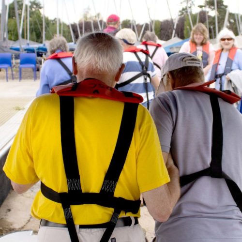 A back view of two people walking to board a sailing boat