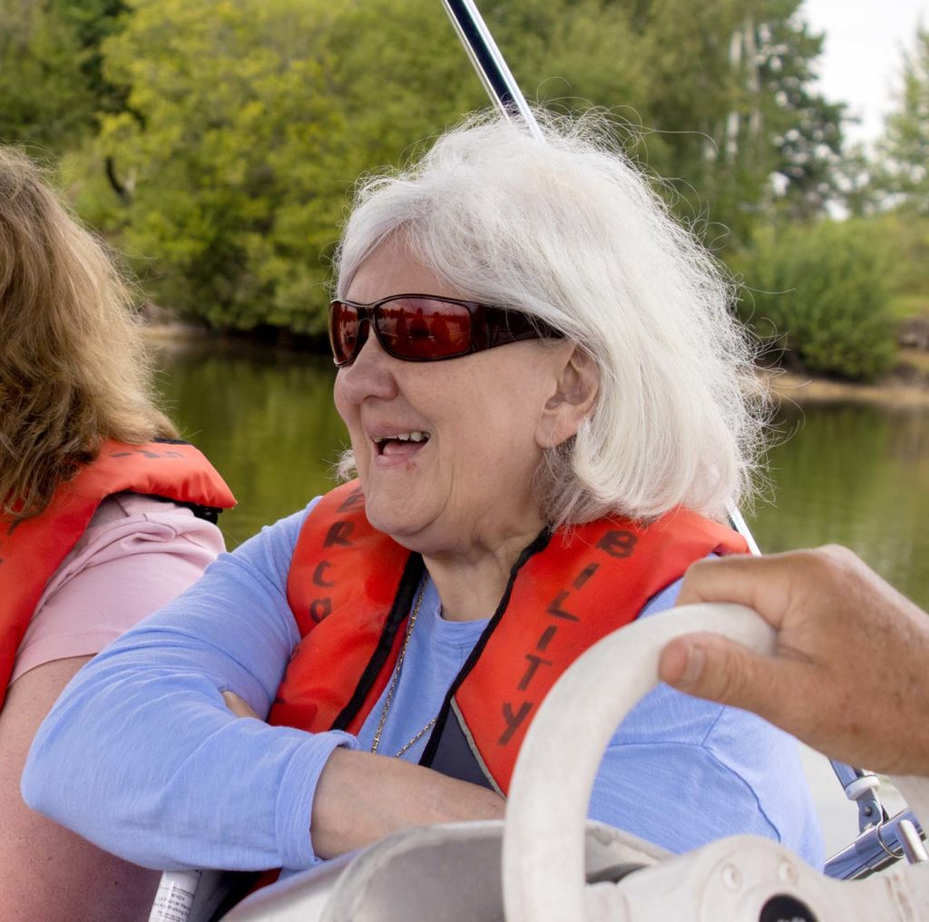 One of our members at the Surrey Coalition of Disabled People sailing event. She is on a boat smiling. 