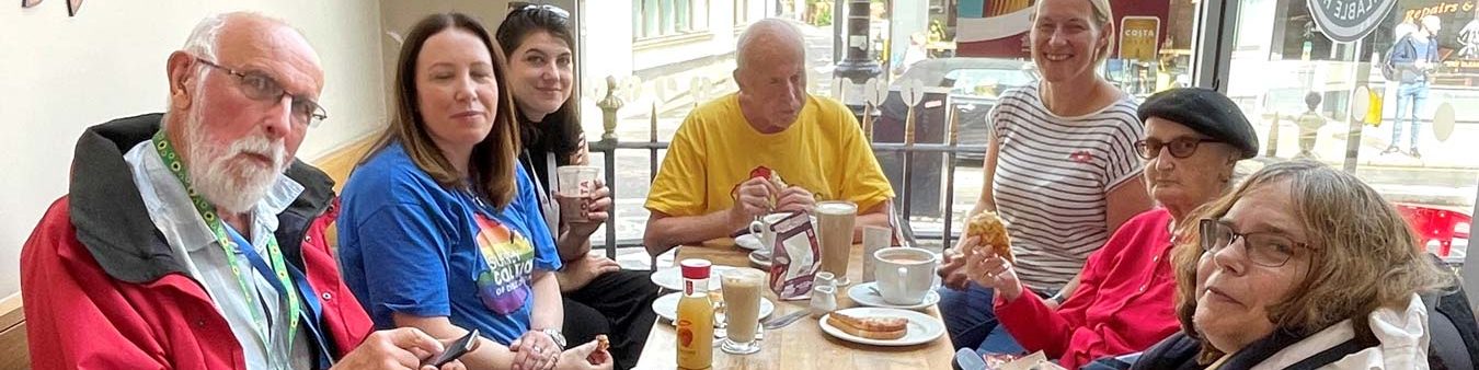 Coalition members and staff around a table at a cafe, enjoying sandwiches