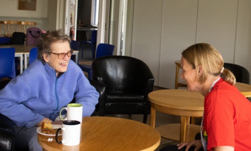 Two people sitting with coffee and talking