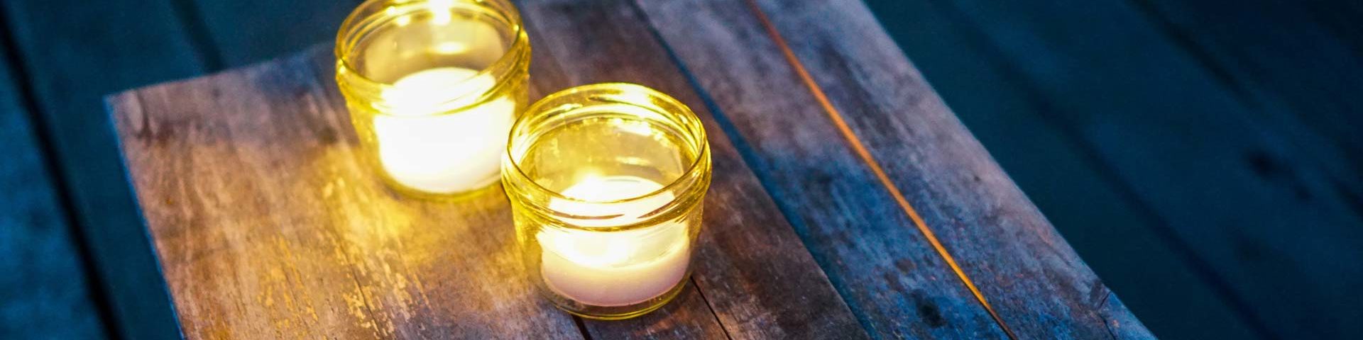 Two tea light candles on a rustic wood bench