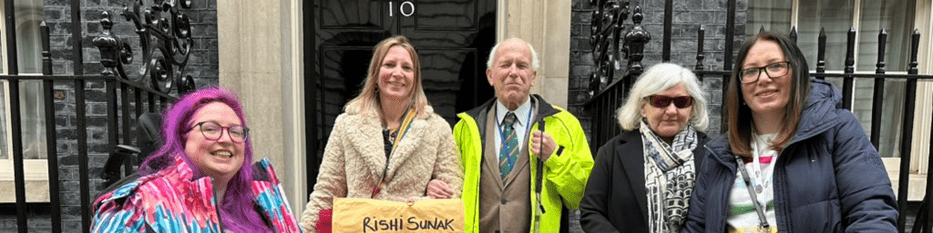 Coalition staff and members in front of the Number 10 door, holding an envelope with the following writing on: Rishi Sunak Prime Minister