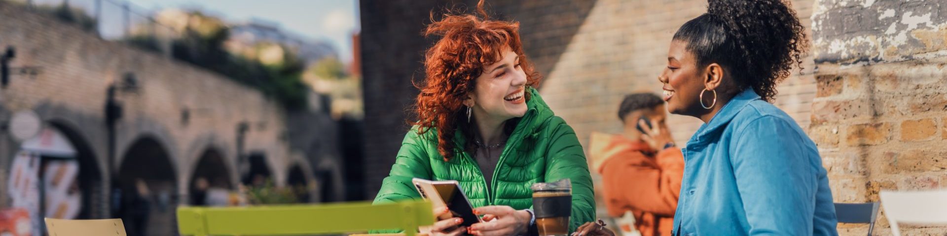 Two women talking and sat outside at a cafe