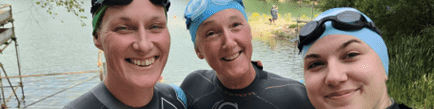 Coalition staff members Katy, Caroline and Charlotte wearing wetsuits with a lake behind them