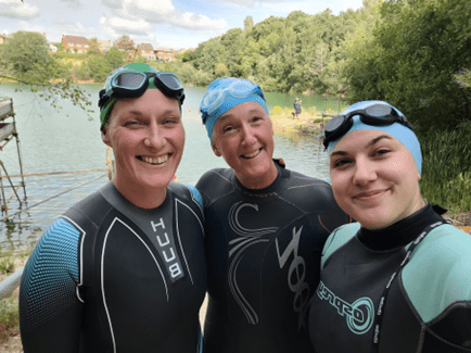 Coalition staff members Katy, Caroline and Charlotte wearing wetsuits with a lake behind them 