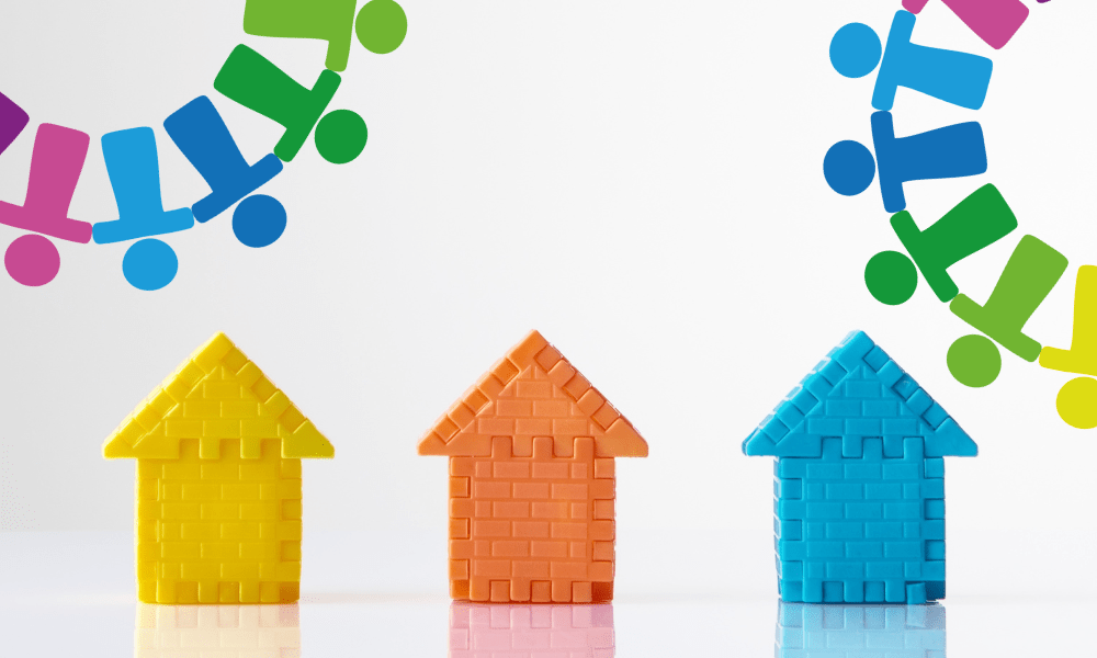 Three building block houses in bright colours, one is yellow, the second is orange and the third is blue.