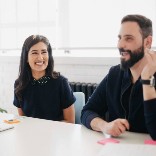 A man and a woman smiling in a meeting