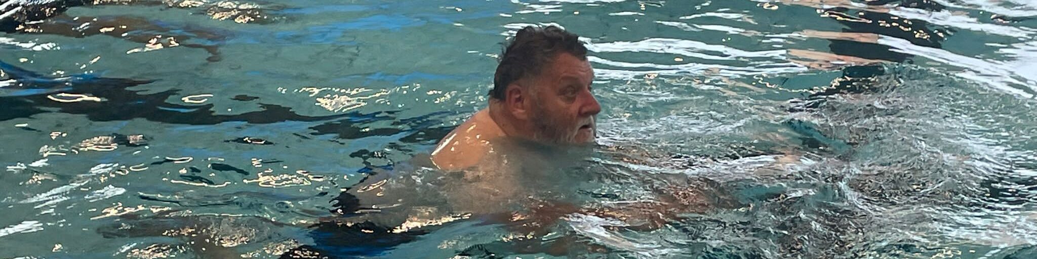 Member David swimming in a swimming pool.