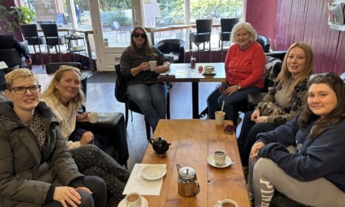 Group having tea and coffee around a table