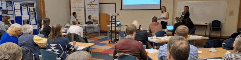 Nikki and Rachel presenting to a room of people at the Surrey Museums Partnership meeting