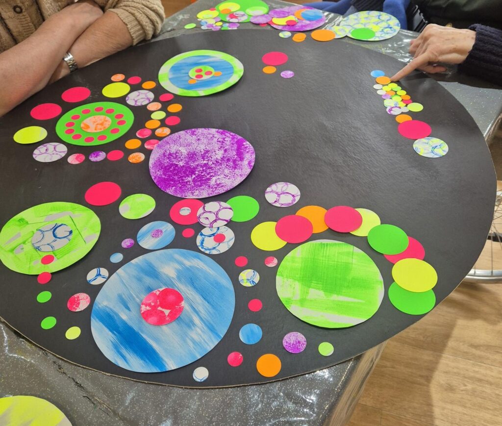 Circular black board with colourful paper with different colours and patterns.