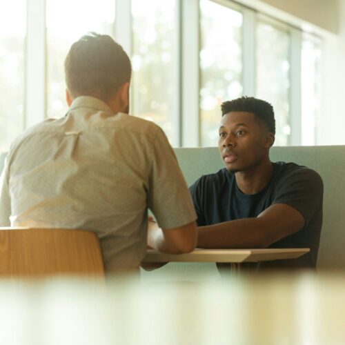 Two men talking sat at a table