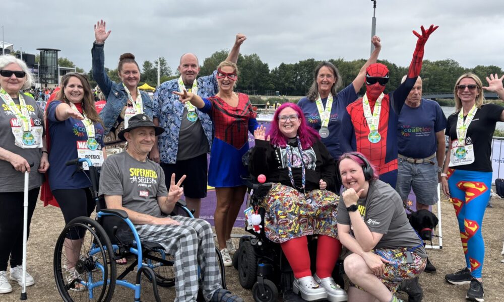 Coalition members and staff with medals around their necks, smiling and pulling superhero poses at Superhero Tri 2025.