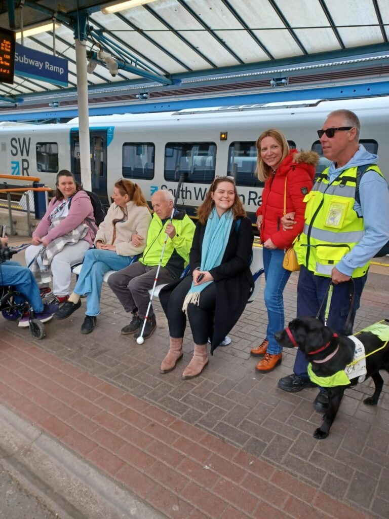 Coalition members and staff at a train platform with a train the background.