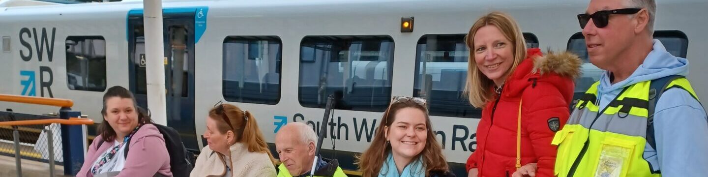 Coalition members and staff at a train platform with a train the background.