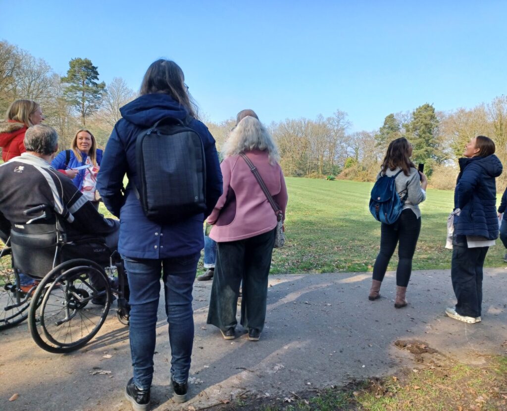Coalition members and staff on path in a park looking at the trees.