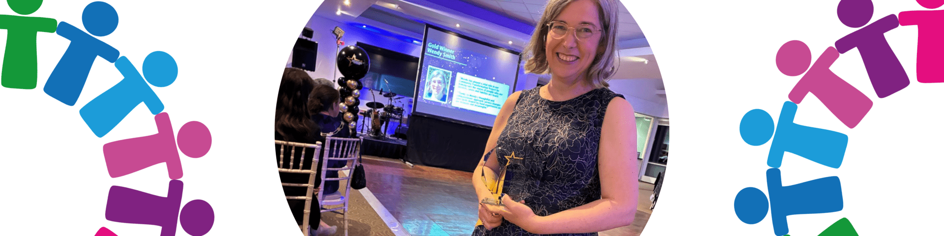 Wendy smiling and holding the award at the staff awards.