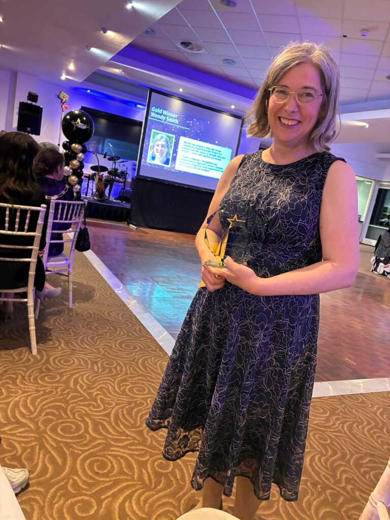 Wendy smiling and holding the award at the staff awards.