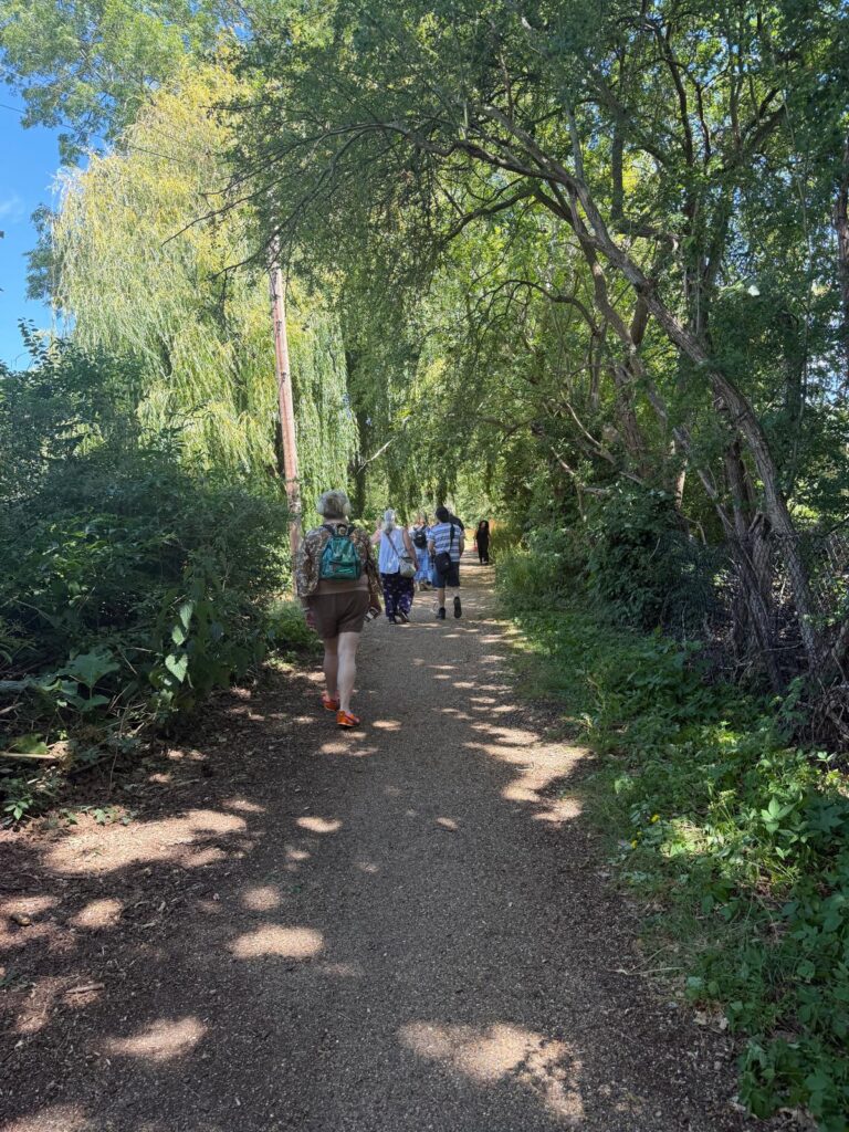 Coalition members walking and wheeling along a tree-lined path