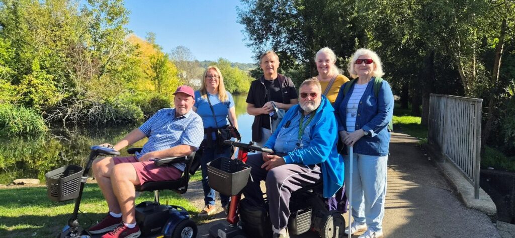 Group of Coalition members with staff member Yasmin on a sunny day next to a river.